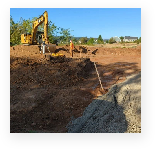 A construction site with a yellow tractor and a pile of dirt.